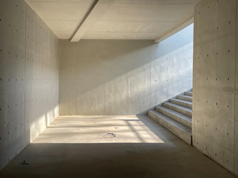 Below-ground concrete room with bare walls and a staircase